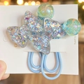 Dettaglio macro di elastici azzurri con fiocchi in resina glitterata e sfere colorate - Celeste