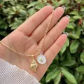 Detailed close-up of 18K gold shell pendant and mother of pearl charm on bead chain necklace - Shell and Mother of Pearl Coin