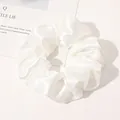 Detail view of a white satin silk scrunchie with soft folds on a minimalist background - White