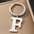 Silver metal letter F keychain on a textured bronze surface with a minimalist design - Letter F