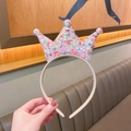 Detailed view of children's princess headband with sparkling colorful sequins on beige crown - Coral