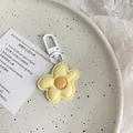 Close-up of a cute yellow flower keychain with a white matte clasp on a ceramic plate - Yellow