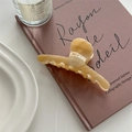 Detailed view of an amber marble acetate hair claw clip on a vintage book - Light Khaki