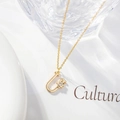 Macro shot of gold letter U pendant featuring a delicate zircon flower on a fine chain - Letter U