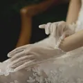 Detail of white sheer tulle bridal gloves with elegant pearl wrist accents and lace trim - V-Shape Beaded