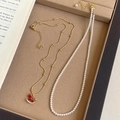 Dettaglio della collana con ciondolo a cavallo in oro 18K e perle su vassoio beige - R4024 Collana a Doppio Strato con Perle e Cavallo a Dondolo