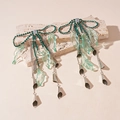 Detail of green rhinestone bow earrings with long tassels and resin leaf accents - Green