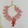 Dettaglio di perle rosa a goccia e ciondolo a aragosta rossa su collana dorata - Aragosta Rosa