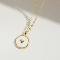 Dettaglio macro di una collana con ciondolo a cuore placcata in oro e smalto bianco - Cuore