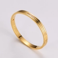 Detail eines polierten Gold-Edelstahlarmreifs mit sechs zarten Zirkonia-Steinen - Gold