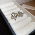 Dettaglio degli orecchini a croce e stella in argento con zirconi in un portagioie - Stile Croce Stella Argento / Argento