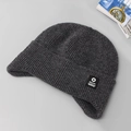 Piatto di un berretto invernale in maglia grigio scuro con paraorecchie ed etichetta - grigio scuro