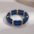 Detailansicht geometrischer tiefblauer Harzperlen und polierter Goldglieder am Armband - Blau