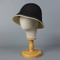 Cappello a secchiello nero intrecciato con bordo beige su un espositore professionale - M (56-58cm) / Nero