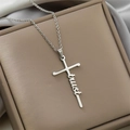 Detailed view of silver stainless steel cross necklace with script 'trust' pendant design - Trust / Steel