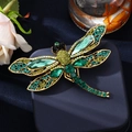 Vintage gold dragonfly brooch with emerald green crystals on a navy jewelry box - Green