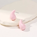 Detail view of pink teardrop enamel stud earrings on a white textured stone background - Pink