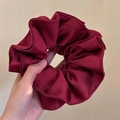 Primer plano de un coletero de satén burdeos con bordes ondulados sostenido a mano - 4 Capas Plisado Grande / Burdeos