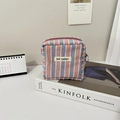 Dettaglio della borsa cosmetica in tela a righe con cerniera sopra un libro bianco - Piccola Borsa Quadrata a Righe Blu Rosa in Cotone e Lino