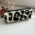 Detalle de estuche de lona con estampado de vaca en blanco y negro y etiqueta de marca - Leopardo/Vaca Beige (Pequeño)