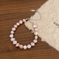 Detail of pale pink freshwater pearls and S925 silver clasp on dark wood surface - Colored Freshwater Pearl Bracelet