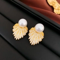 Close-up of fan-shaped pearl earrings with gold plating and zircon inlay on a black tray - Silver Pin - White Pearl Zirconia Leaf Stud Earrings / Gold White Pearl Style