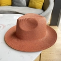 Detailed close-up of orange woven straw fedora hat on a marble tabletop surface - Brick Red