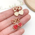 Close-up of a small heart-shaped red cherry pendant with rhinestones on a finger - KC Gold Red Bowknot Rhinestone Cherry (23400)