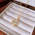 Macrodetail van gouden bloemketting met blauwe kattenoogstenen en parels in doosje - Klavertje Vier Bloem Ketting