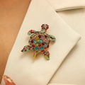 Broche tortue vintage avec strass colorés sur le revers d'un costume beige - Coloré