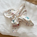 Detailed view of floral polka dot hair scrunchie with brand tag on white fabric - Colorful Polka Dot Scarf