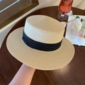 Cappello di paglia beige a tesa piatta con ampio nastro nero su un tavolo di legno - Top Piatto Beige (D-380)