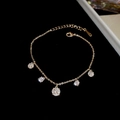 Gros plan détaillé du bracelet plaqué or avec breloques en zircon sur velours noir - Style à Cinq Zircons Ronds Dorés / Doré