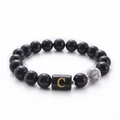 Detail view of black onyx and white turquoise beads with a golden letter C charm bracelet - Letter C
