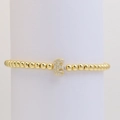 Detailed macro view of gold-plated bead bracelet with cubic zirconia letter E charm - Letter E