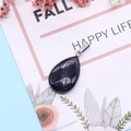 Deep blue sandstone teardrop pendant with silver bail on a floral decorative card - Blue Sandstone