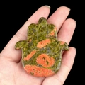 Hamsa Hand pendant carved in green and orange natural stone held in palm - Unakite