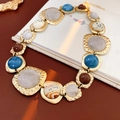 Dettaglio di una collana vintage dorata con texture martellata e gemme colorate - Collana / Oro