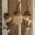 Adorabili pupazzo di neve e Babbo Natale in peluche appesi a una finestra di legno bianco - Targa in Legno Marrone MERRY CHRISTMAS Combinazione di Tre Bambole