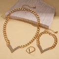 Detailoverzicht van 3-delige gouden sieradenset met V-vormige strasstenen op beige steen - 3-delige set / Goud