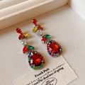 Macro shot of silver drop earrings with red stones and multi-colored gems on a tray - Earrings / Colorful