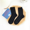 Calze nere con bordo a volant e classica trama a trecce su un vassoio elegante - Nero Intrecciato