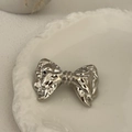 Close-up of a silver hammered metal bow hair accessory on a white ceramic plate - Silver-Bow