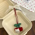 Detail of cute cherry cat plush charm with lace bow and embroidered details on red fabric - Cherry Cat