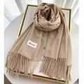 Close-up of soft beige cashmere scarf with elegant fringe details and woven label - Khaki