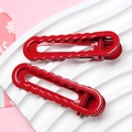 Pair of glossy red wavy metal hair clips with smooth finish in a minimalist style - Christmas Red