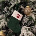 Green knit Christmas stocking with red dog paw embroidery hanging on a snowy tree - Green/Dog Paw