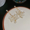 Vista macro degli orecchini a mughetto con perle e cristalli su un piatto di ceramica - Perno in argento-Bianco
