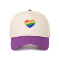 Dettaglio del ricamo a cuore arcobaleno su un cappellino da baseball beige e viola. - Viola