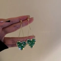 Dettaglio di orecchini a cuore in cristallo verde con nappe dorate e finitura lucida - 38# Perno in Argento - Cuore di Cristallo Verde